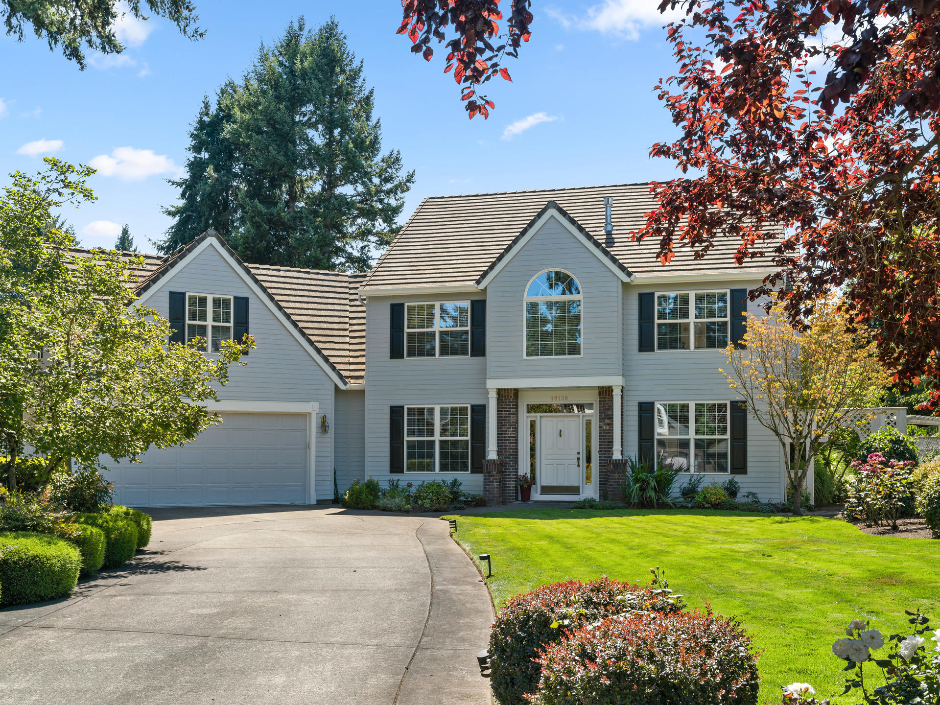 Exterior Traditional home in Tualatin with green grass and driveway up to garage
